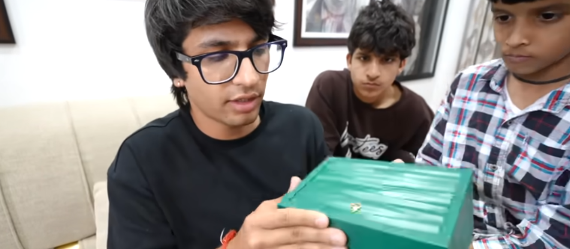 A young men and a kid (Sourav Joshi and Kunali) hold a green box while unboxing a Rolex watch, showcasing excitement and anticipation.