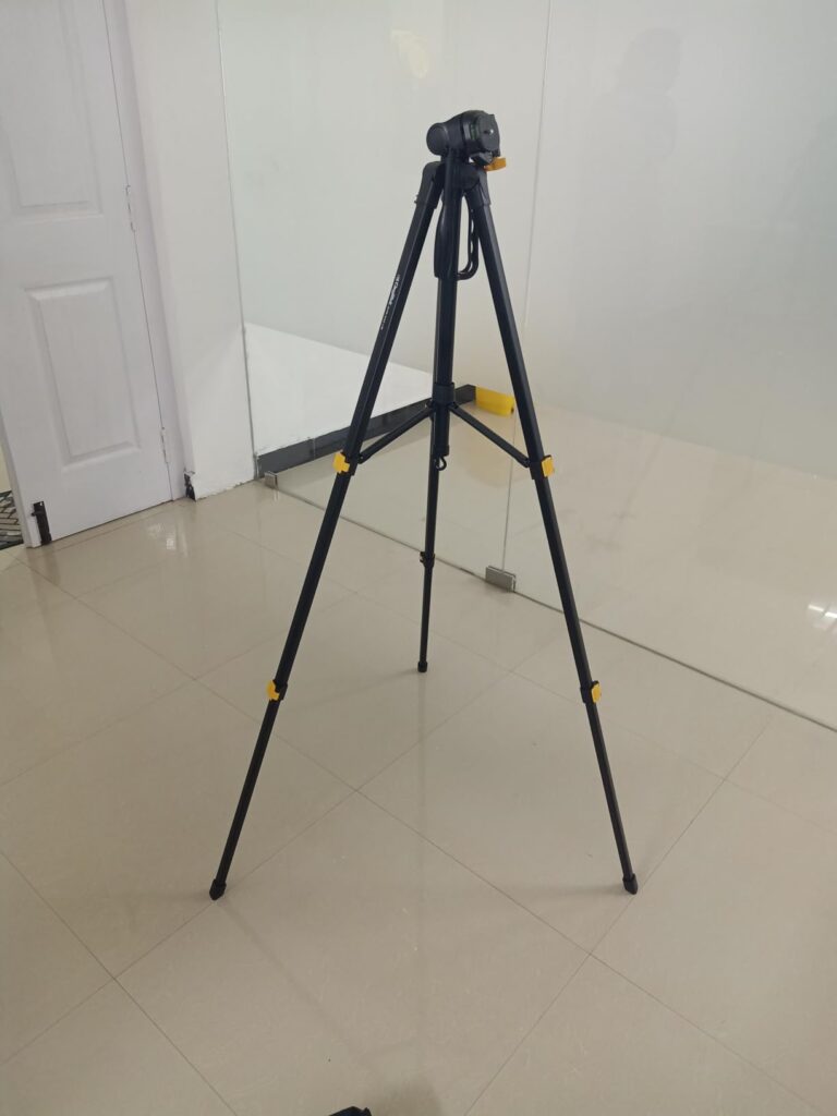 Digitek DTR 550 LW foldable tripod stand placed on floor showing adjustable height and flip lock legs